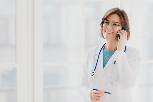 Une femme médecin ou chirurgienne heureuse donne une ordonnance via un téléphone mobile