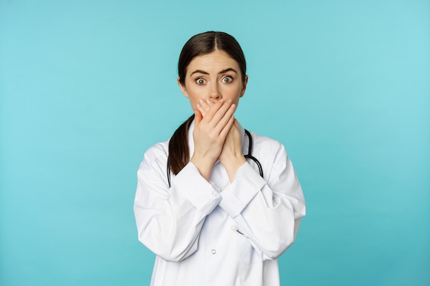 Une femme médecin choquée et inquiète qui se couvre la bouche avec les mains qui a l'air surprise de camer...