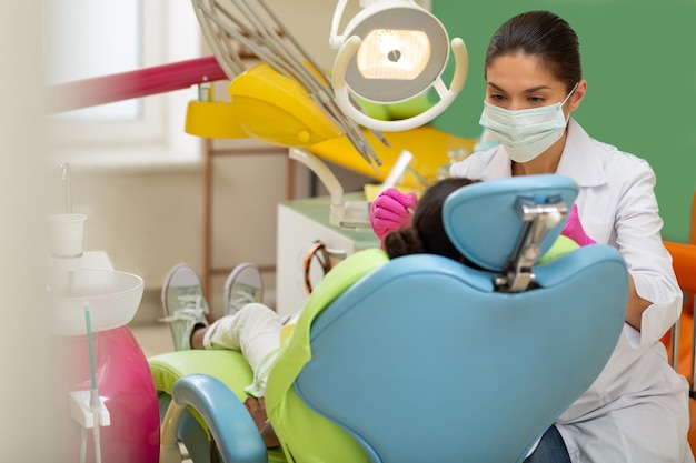 Femme médecin concentrée se penchant sur un petit patient