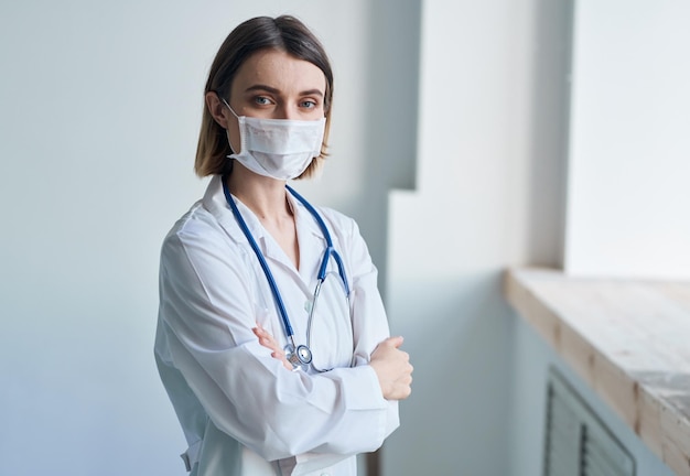 Femme médecin dans un masque médical avec un stéthoscope autour du cou