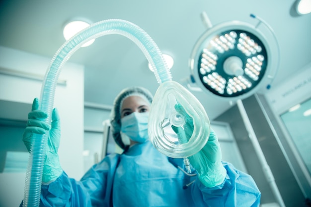 Femme médecin debout dans la salle d'opération et se prépare à mettre son patient sous narcose