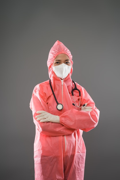 Femme médecin debout regardant la caméra portant un EPI et un masque avec les mains jointes