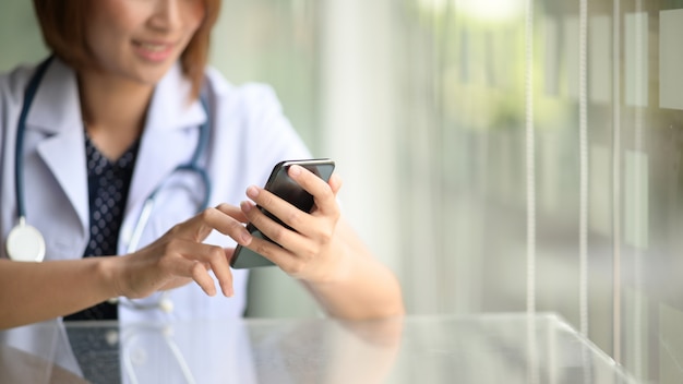 Femme médecin détenir un smartphone mobile et pointer sur l&#39;écran tactile