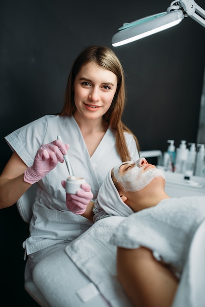 Femme médecin détient la crème et le pinceau dans les mains