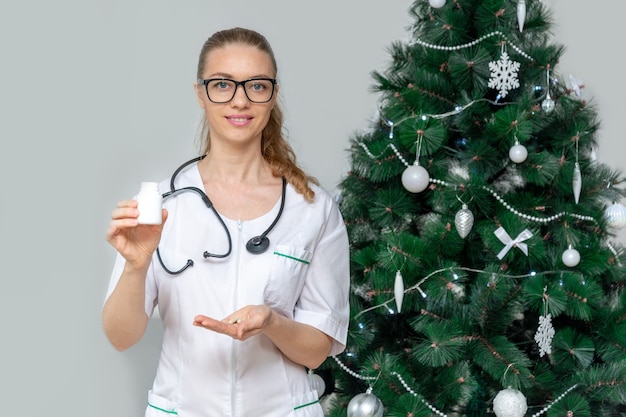 Une femme médecin détient des pilules dans l'espace d'un arbre de Noël