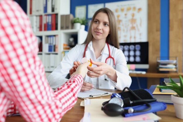 Femme médecin donnant un pot de médicaments au patient en clinique