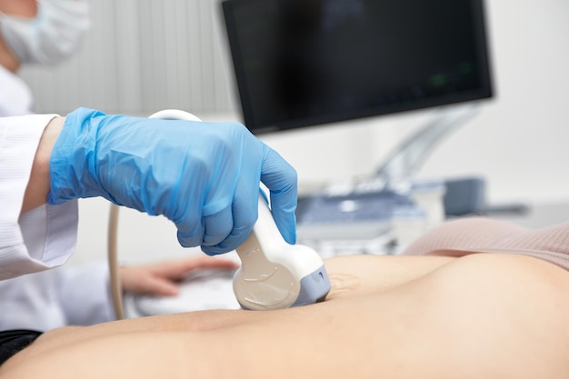 Une femme médecin donne au patient une échographie abdominale féminine Échographie entre les mains d'un médecin