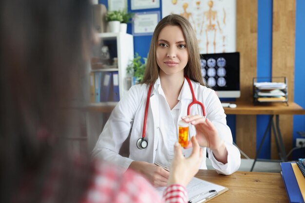 Femme médecin donne au patient un récipient en plastique rempli de médicaments stagiaire annonce des pilules