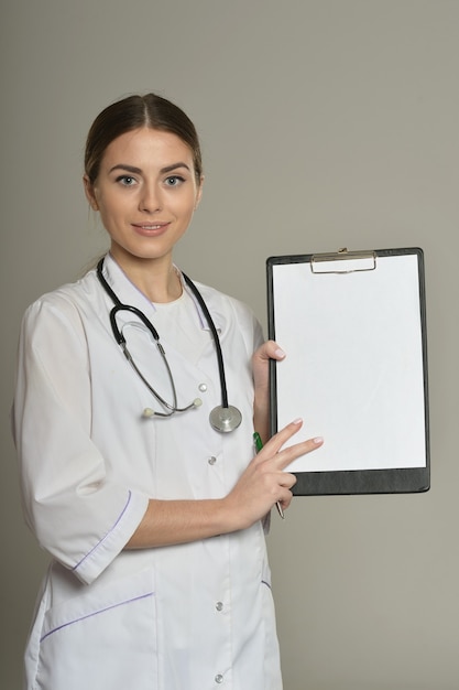 Femme médecin avec un dossier, debout isolé sur fond gris