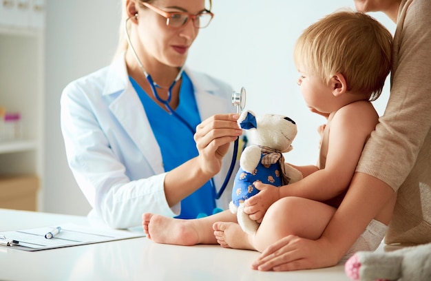 Une femme médecin écoute un enfant avec un stéthoscope en clinique