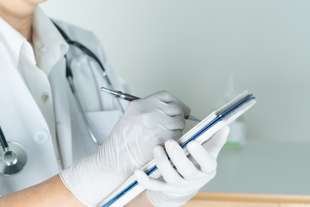 Femme médecin écrit des informations médicales dans un cahier à l'hôpital