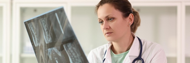 Femme médecin examinant le film radiographique du patient assis à l'hôpital thérapeute