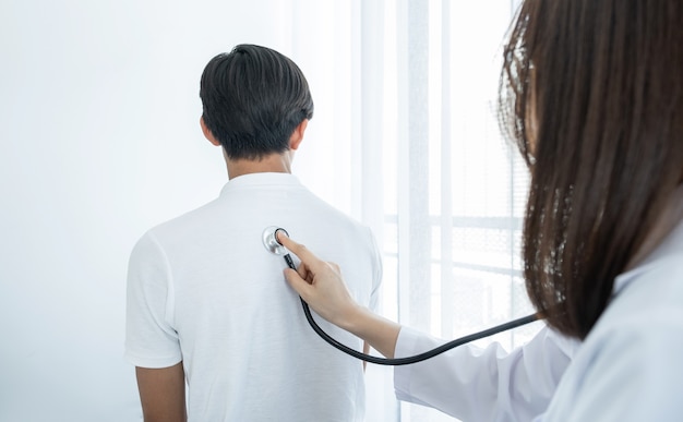 Photo femme médecin examinant la santé des patients de sexe masculin avec un stéthoscope.