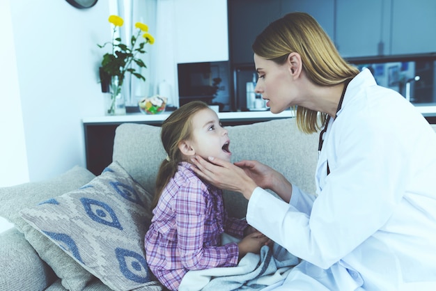 Femme médecin examine jolie enfant malade à la maison