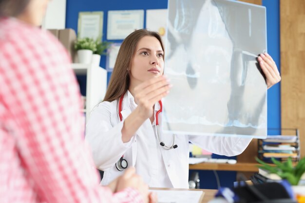 Femme médecin examine la radiographie du patient agrandi