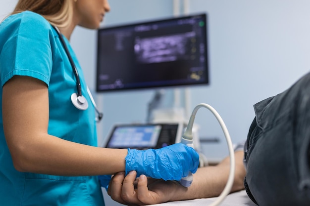 Femme médecin faisant un examen échographique des veines du bras du patient dans son bureau Jeune homme passant une échographie dans une clinique Travail de médecin Recherche médicale