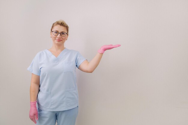 Une femme médecin en gants roses pointe sa main sur le côté sur un fond clair