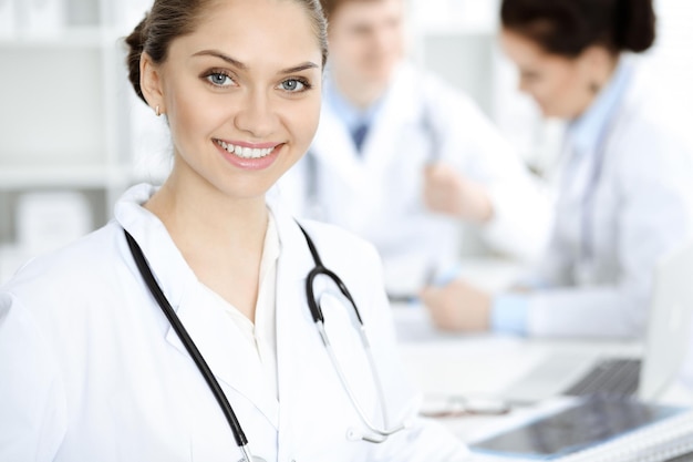 Une femme-médecin heureuse et souriante assise et regardant la caméra lors d'une réunion avec le personnel médical.