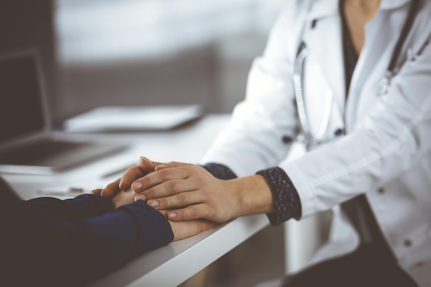 Une femme-médecin inconnue rassure sa patiente, en gros plan. Le médecin consulte et donne des conseils à une femme. Concepts d'éthique médicale et de confiance. L'empathie en médecine.