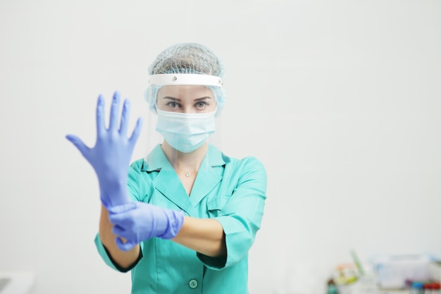 Femme médecin ou infirmière en uniforme, masque médical, masque facial met des gants. Coronavirus (COVID-19. Fille, femme.