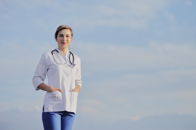 Femme médecin ou infirmière en uniforme médical sur fond de ciel nuageux