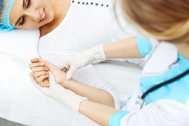 Femme médecin et jeune femme patiente à l'hôpital. Les médecins examinent le pouls de la fille allongée sur le lit, vue d'en haut. Aide médicale et assurance en soins de santé, meilleur traitement et concept de médecine.