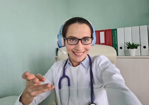 Une femme médecin en ligne professionnelle dans un casque parle en regardant la caméra