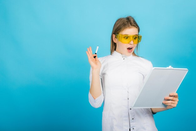 Femme médecin à lunettes jaunes et bureau sur fond bleu