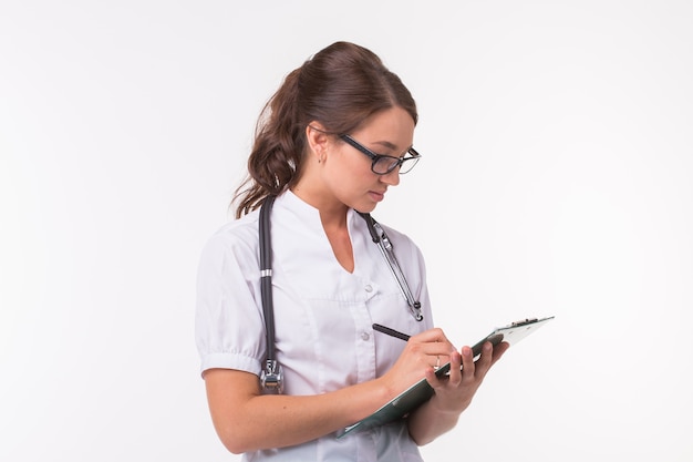 Femme médecin main tenant un stylo écrit quelque chose sur le presse-papiers sur fond blanc.