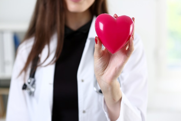 Femme médecin médecine mains tenant coeur rouge