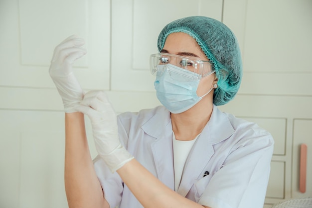 Une femme médecin met un gant avant la chirurgie