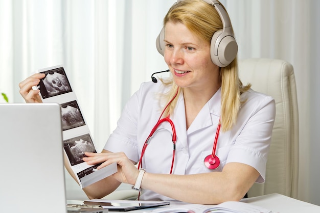 Femme médecin montrant à sa patiente une image échographique de son bébé sur le télétraitement de l'ordinateur portable