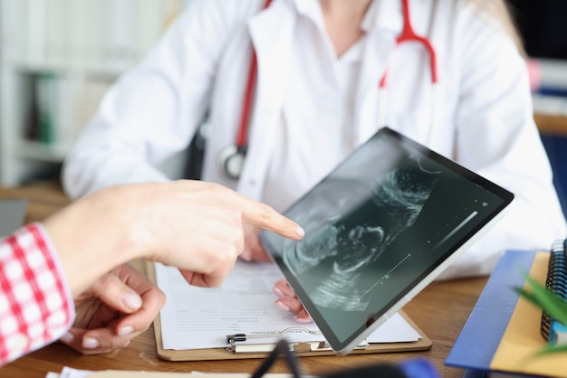 Femme médecin montrant une tablette numérique avec photo échographique de fœtus en gros plan clinique