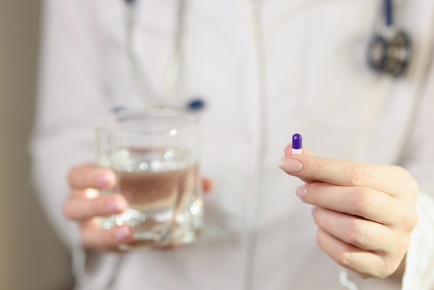 Une femme médecin montre une seule pilule dans sa main en gros plan