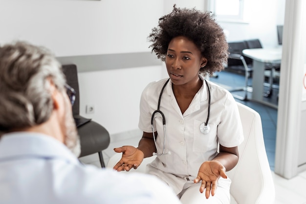 Femme Médecin Noire Et Homme Senior Communiquant Dans Une Salle D'attente à L'hôpital.