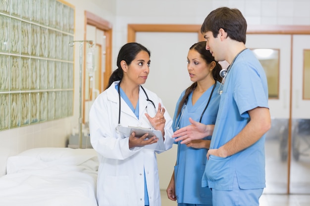 Femme médecin parlant à un homme et une infirmière dans un couloir