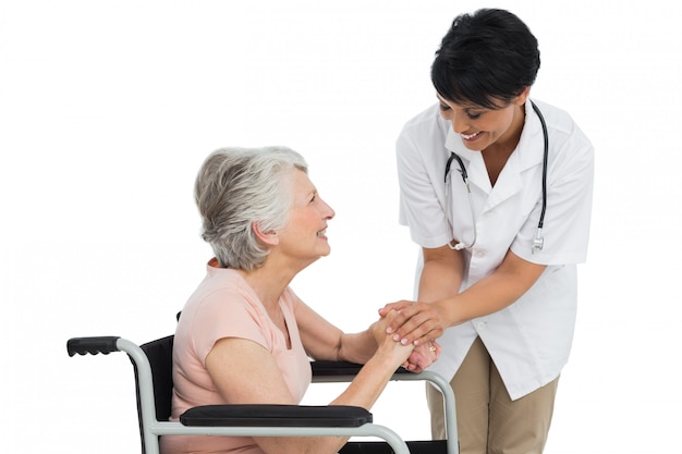 Femme médecin parlant à un patient âgé en fauteuil roulant