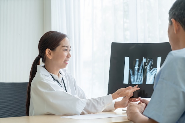 Femme médecin et patient asiatique discutant de quelque chose tout en étant assis à la table