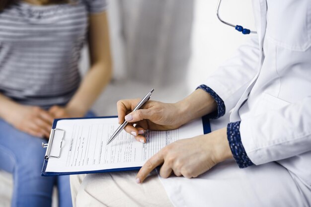 Femme médecin et patiente inconnue discutant de l'examen de santé actuel alors qu'elle était assise dans un salon confortable. Concept de séjour à la maison pendant la pandémie de coronavirus et la quarantaine d'auto-isolement