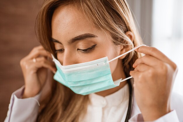 Femme médecin portant un masque médical debout regardant la caméra