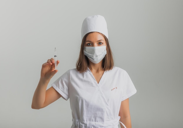 Une femme médecin portant un masque médical tient une seringue dans ses mains. notion de vaccination.