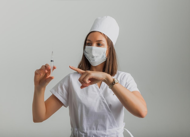 Une femme médecin portant un masque médical tient une seringue dans ses mains. notion de vaccination.