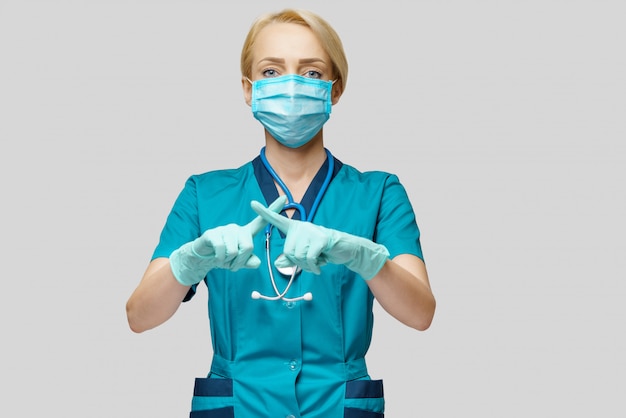 Femme médecin portant un masque de protection et des gants en latex, geste d'arrêt