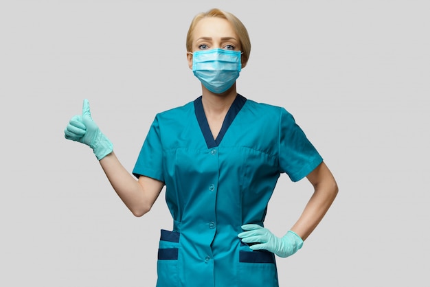 Femme médecin portant un masque de protection et des gants en latex montrant le grand pouce vers le haut