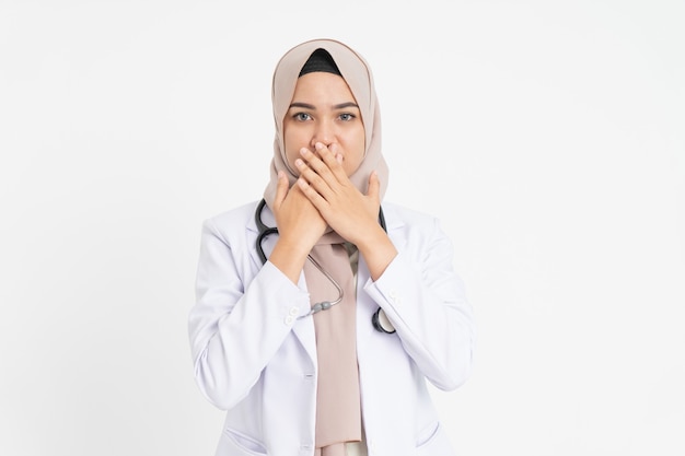 Femme médecin portant un uniforme de costume blanc couvrant sa bouche avec les deux mains