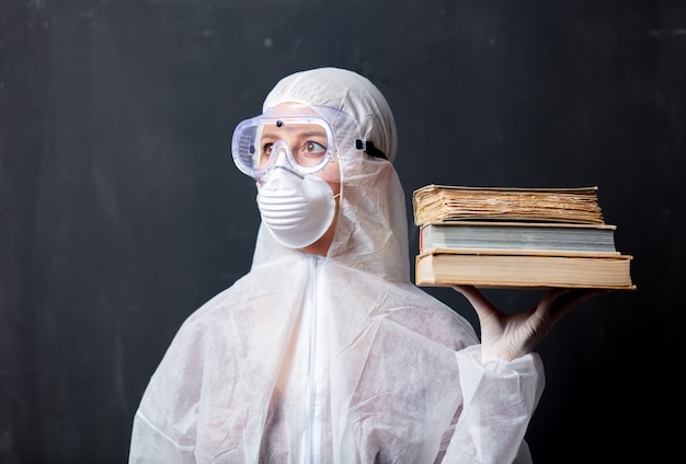 Femme médecin portant des vêtements de protection contre le virus avec des livres