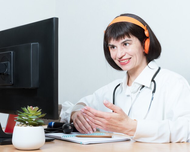 Une femme médecin porte un casque passe un appel vidéo en ligne, discute, gestes