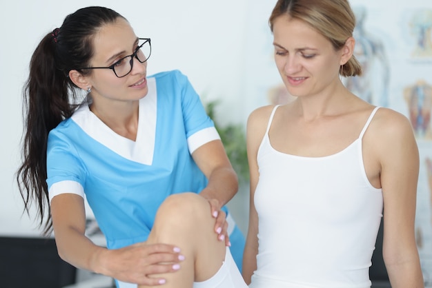 Une femme médecin procède à un examen physique de l'articulation du genou du patient