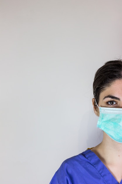 Photo femme médecin en pyjama de travail avec masque de protection respiratoire contre les coronavirus. blanc sur le côté.