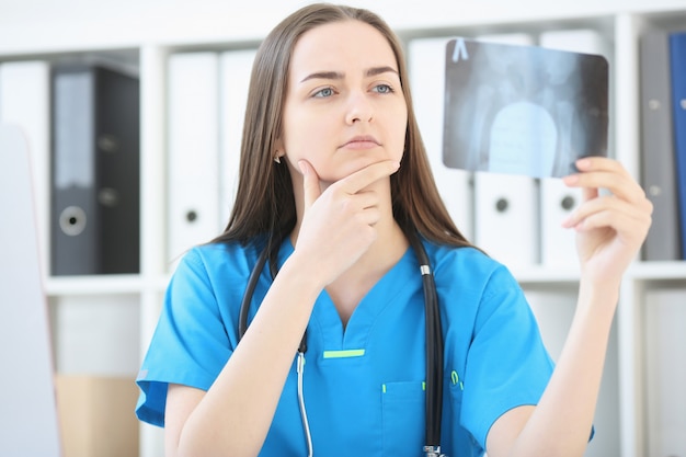 Une femme médecin avec un regard sérieux examine une radiographie